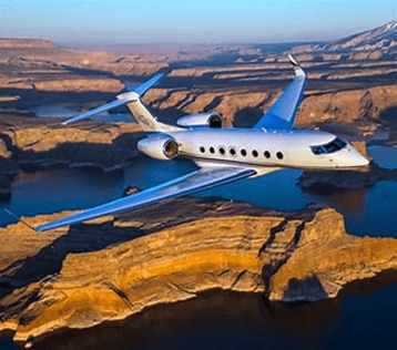 A sleek private jet soars over rugged canyons and a shimmering lake, showcasing luxury travel amidst stunning natural scenery.