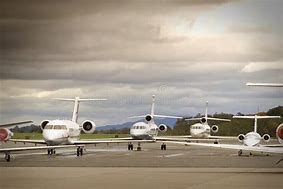 Four private jets lined up on a runway under a cloudy sky, showcasing luxury air travel options. Ideal for a discussion on private aviation.