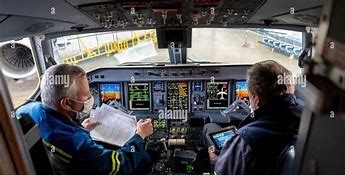 Pilots in an aircraft cockpit review flight plans and instruments. The image highlights the operational environment of aviation safety and teamwork.